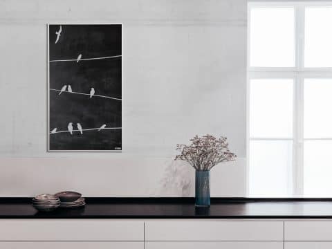 Die Tafelheizung mit weißen Vögeln aufgezeichnet hängt an einer hellen Wand einer Küche.