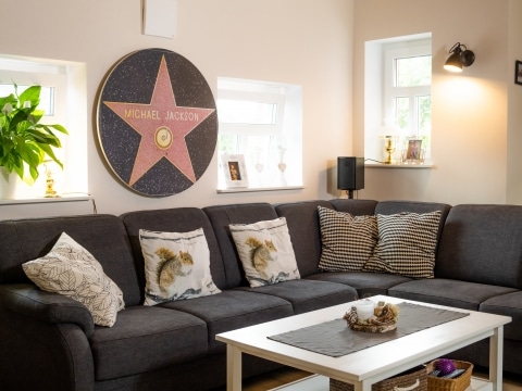 Die bedruckte Round beheizt ein schönes Wohnzimmer mit einer Couch im Vordergrund auf der Polster liegen.